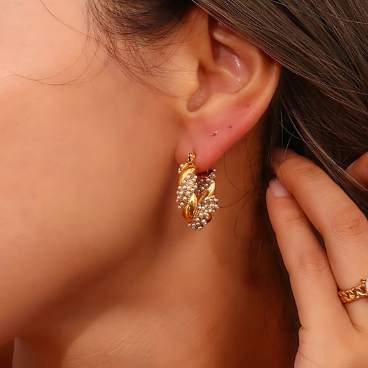 Close-up of a gold bracelet with pearl detail styled with matching earrings.