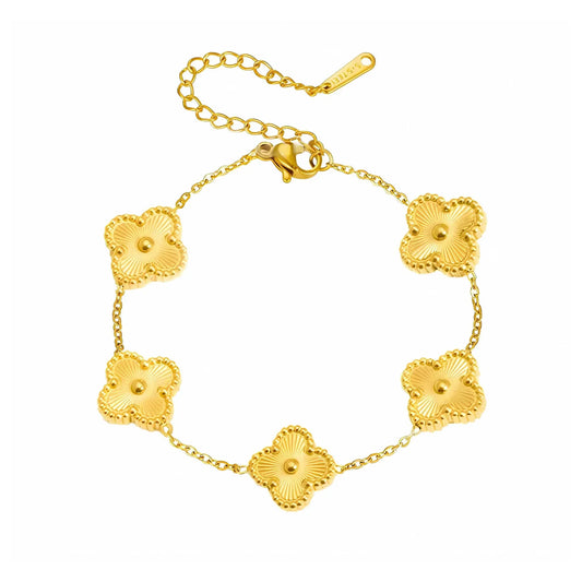 Gold chain bracelets stacked on a woman’s wrist in a minimal outfit.