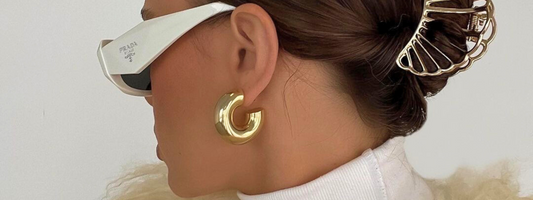 Nahaufnahme einer goldenen Kette mit Zirkonstein auf hellem Stoff.