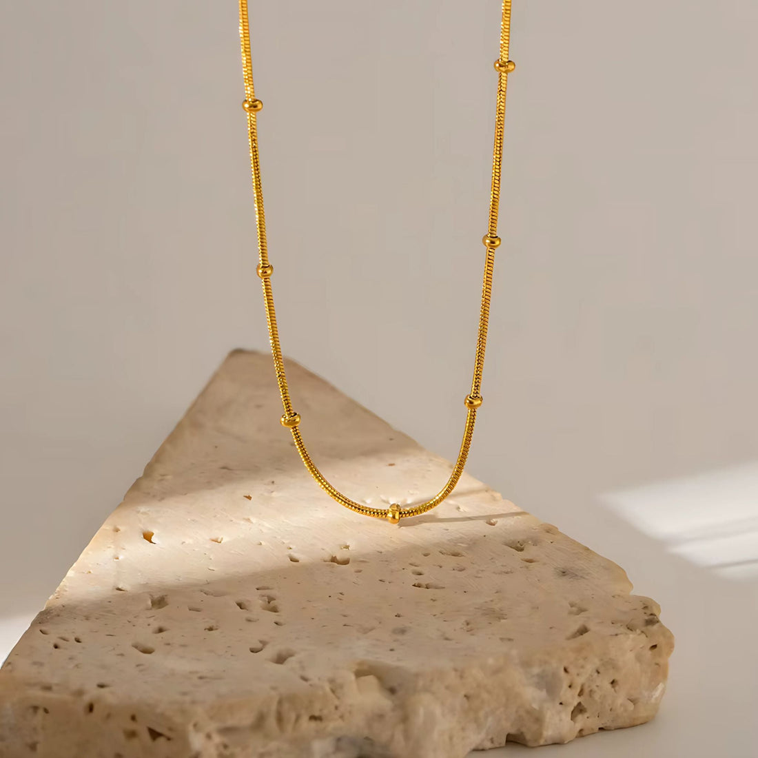 Goldplattiertes Armband und Creolen als elegantes Schmuck-Duo auf weißem Hintergrund.