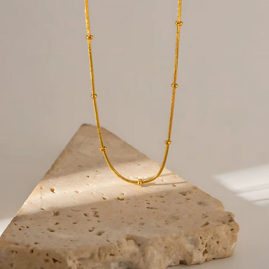 Goldplattiertes Armband und Creolen als elegantes Schmuck-Duo auf weißem Hintergrund.