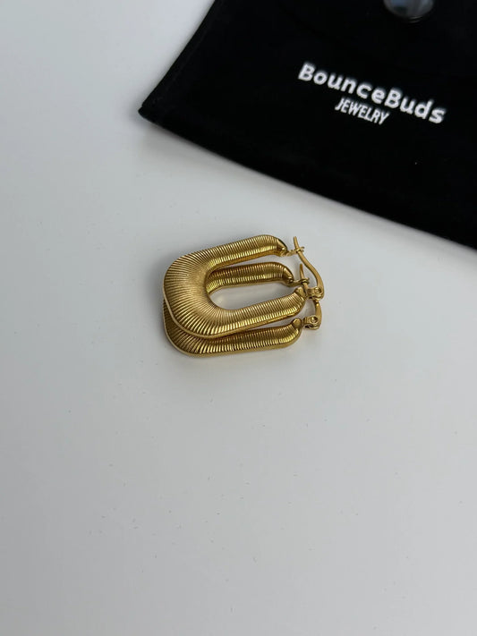 Flatlay of minimalist gold jewelry pieces from the Basic Collection on neutral background.