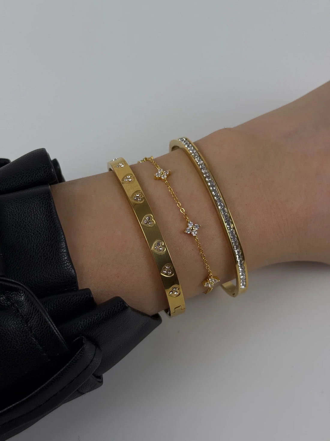 Gold bracelet with pearl detail styled on a white blouse.