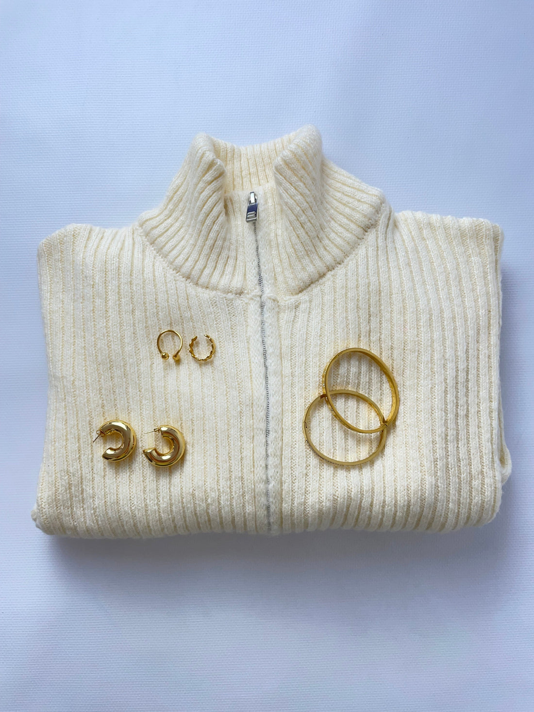 Woman in a city street wearing gold hoops and a layered minimalist necklace.