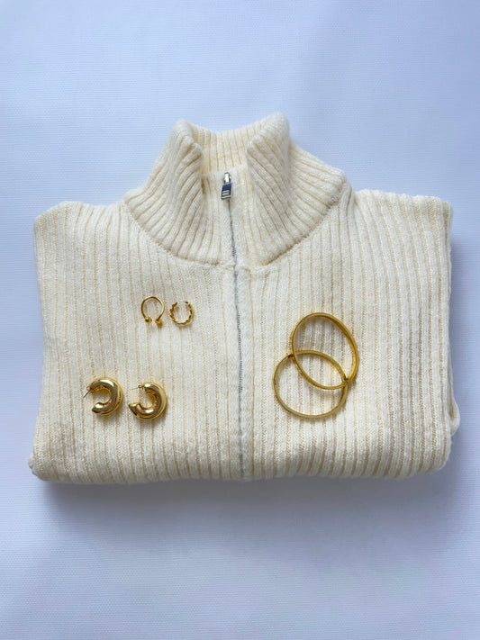 Woman in a city street wearing gold hoops and a layered minimalist necklace.