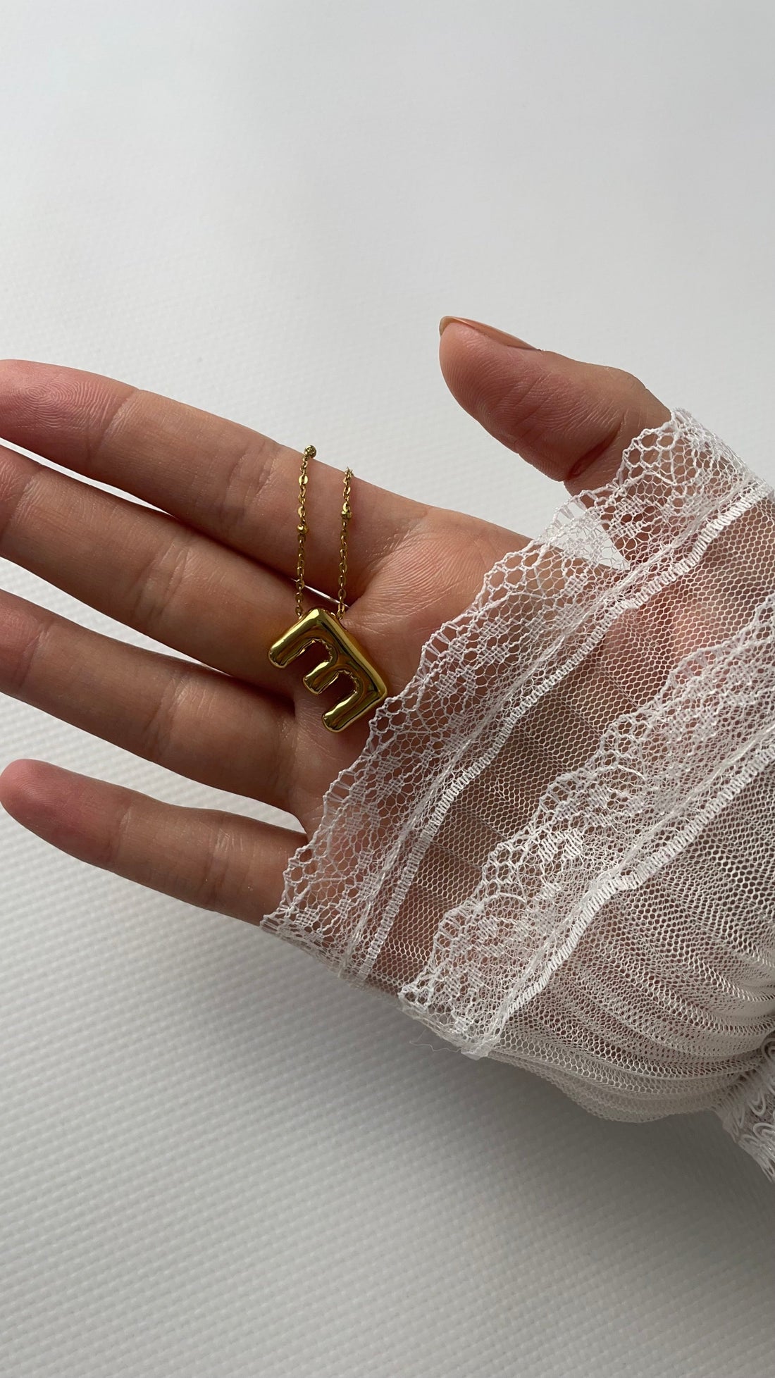Gold-plated initial necklace styled with a white blouse.