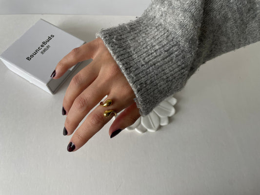 Woman wearing a chunky gold necklace over a beige turtleneck sweater in autumn sunlight.