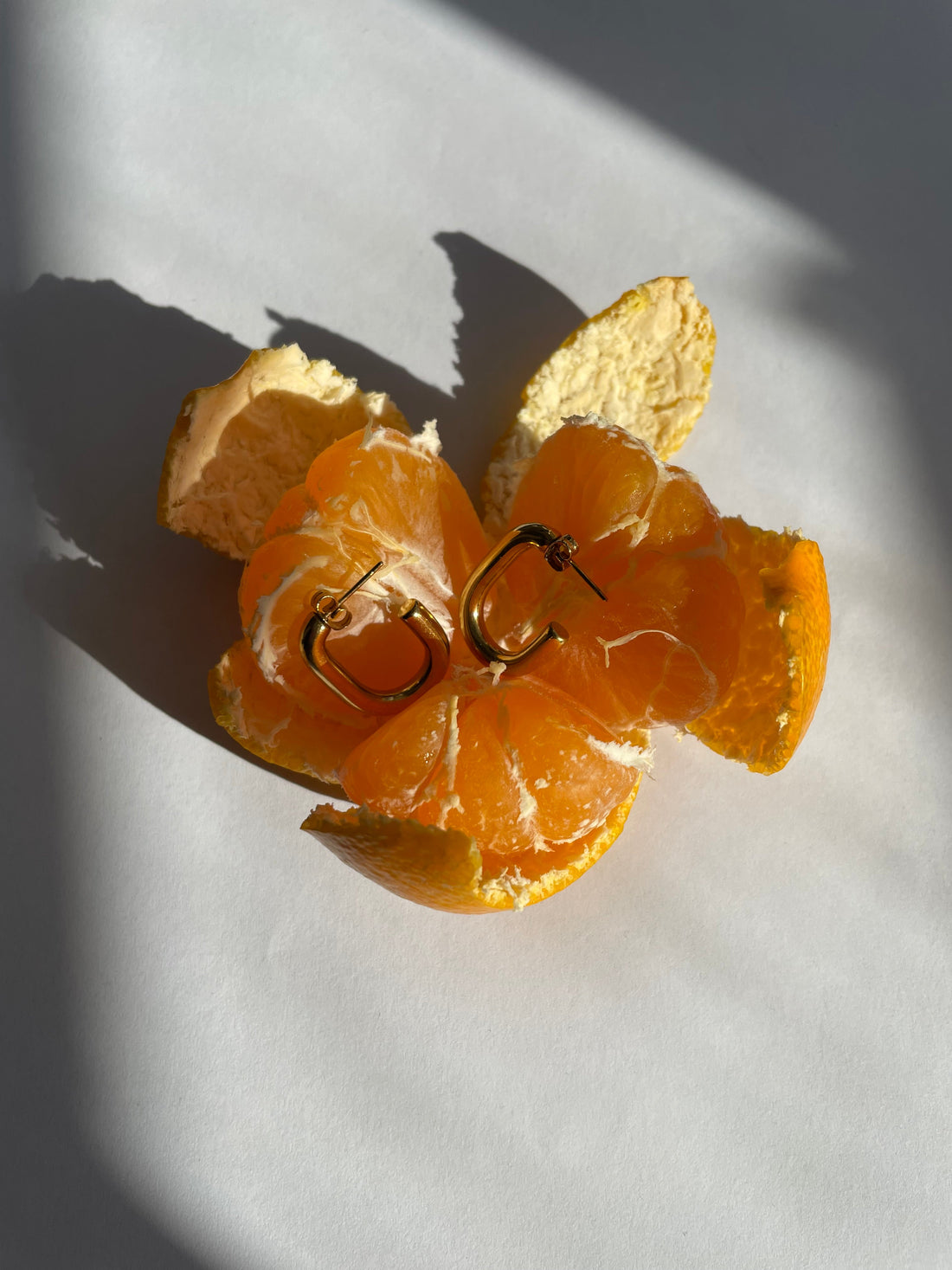 Woman wearing chunky gold necklace and hoop earrings with a cream winter sweater.